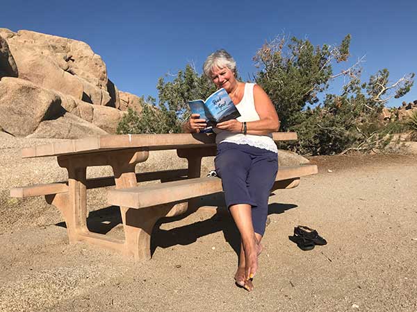 Carmen Mendoza at a picnic table reading her book Road to Soul.